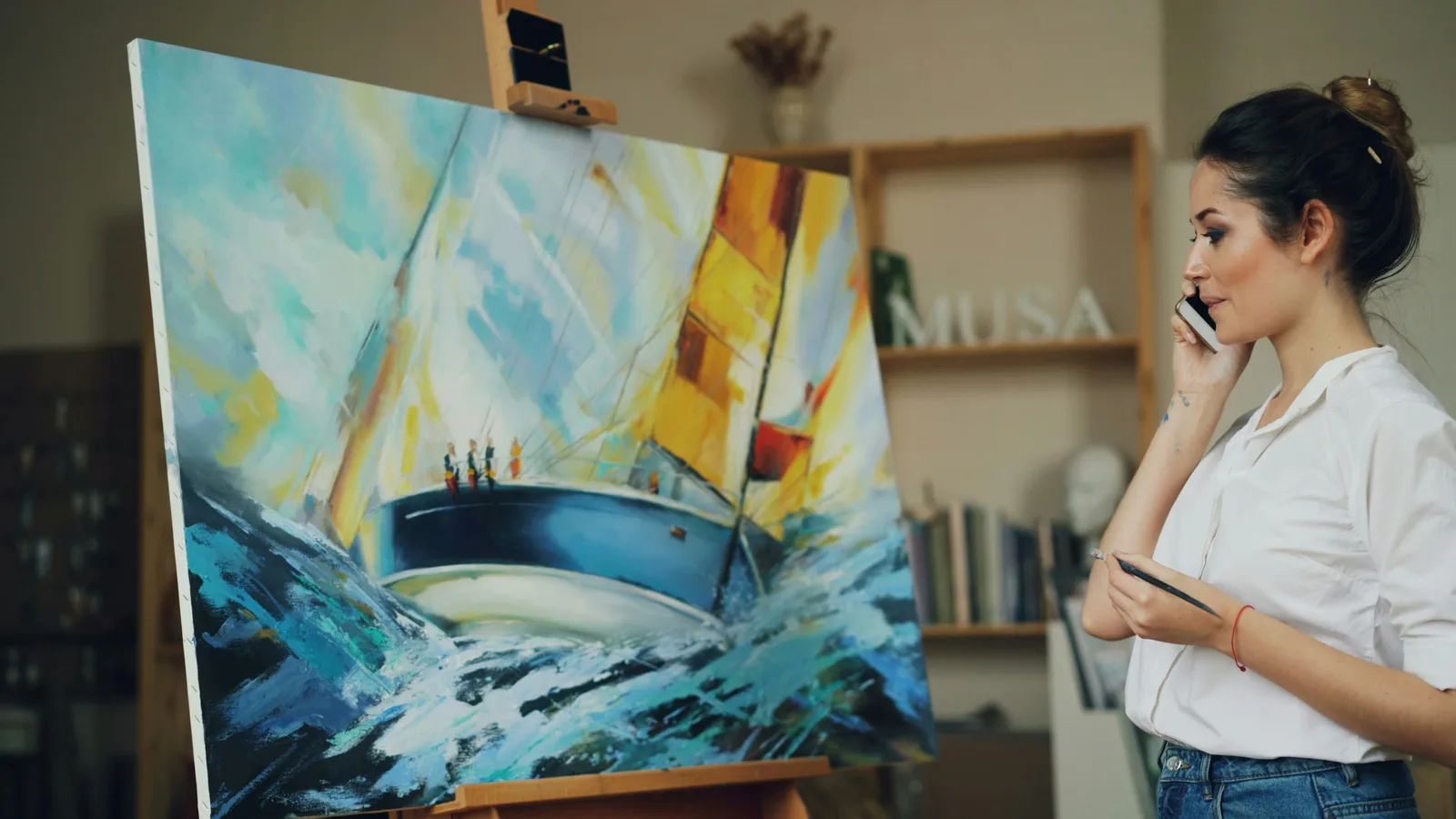 Artist taking a phone call beside a large painting in her studio