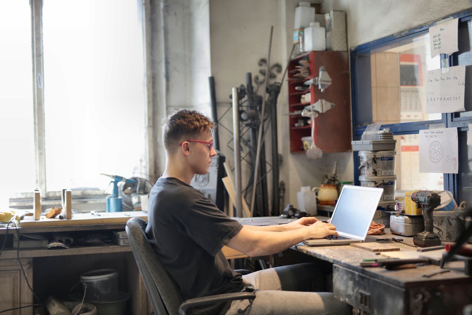 A service-business owner working on a laptop at a tool-filled workshop bench